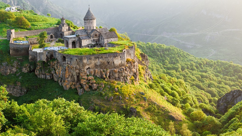 Tatevklostret i Armenien, som ligger p� ett klipputspr�ng med branta bergssidor, dalen nedanf�r �r fylld av ljusgr�na l�vtr�d.