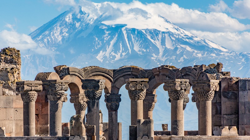 Ruin med ornamenterade kolonner i Armenien, med berget Aragats i bakgrunden.