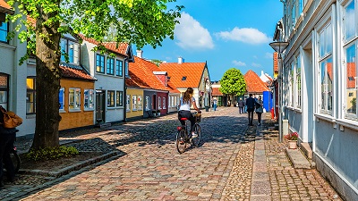 Pittoresk gatuvy från Odense, med låga färgstarkt målade hus och kullerstensgata.