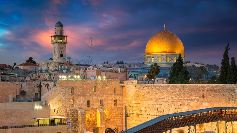 Övre delen av Klagomuren och Klippdomen, vars guldkupol lyser upp mot kvällshimlen med mörkblå och rosa moln.