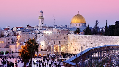 Vy ver Tempelberget och Klagomuren i kvllningen, Klippdomens guldkupol lyser mot en rosaaktig himmel.