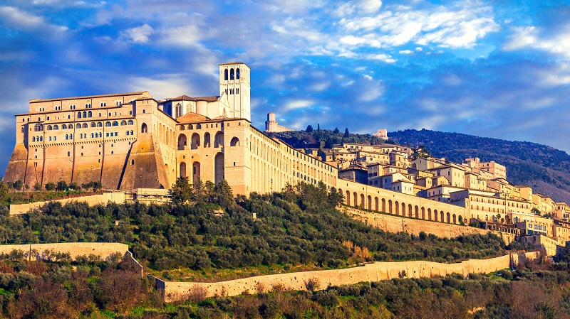 Franciscusbasilikan i Assisi från väster med mäktiga murar och staden som breder ut sig på kullen bakom.