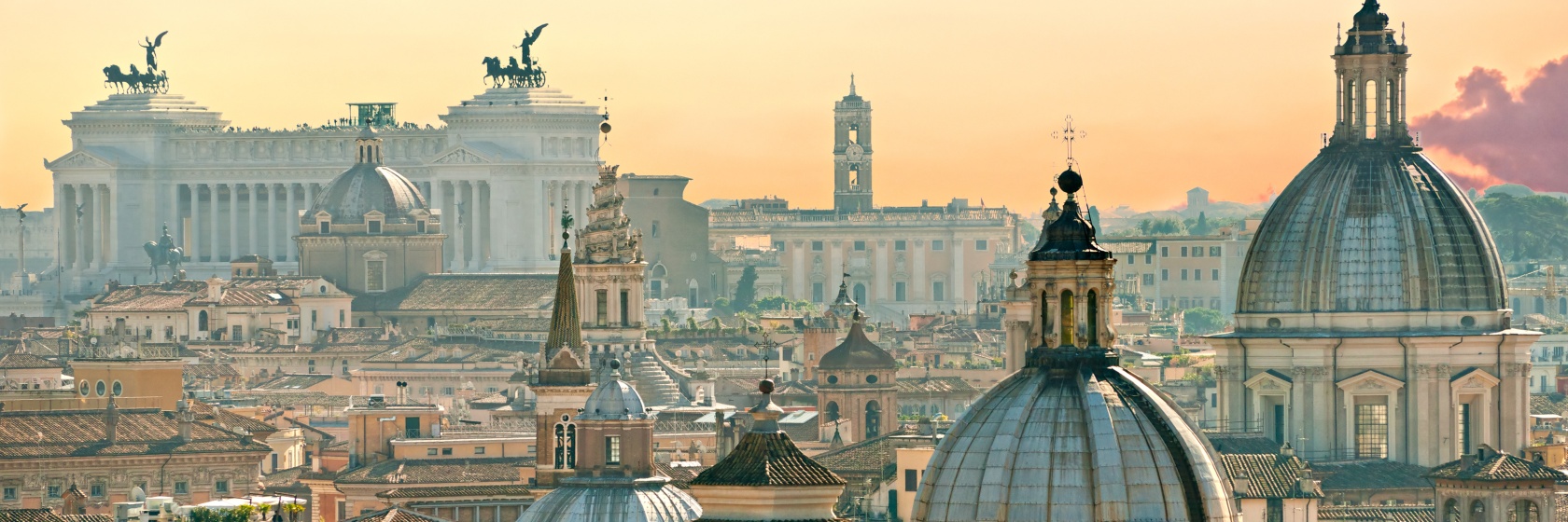 Takvy �ver Rom med m�nga kyrktorn och Victor Emmanuel II-monumentet, mot en gulaktig morgonhimmel.