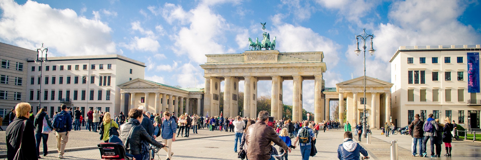 Brandenburger Tor i förmiddagsljus, med fullt av människor i rörelse.